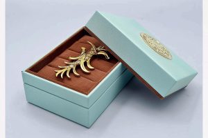 Elegant mint green jewelry box with brown velvet insert, perfect for brooches and fine jewelry.