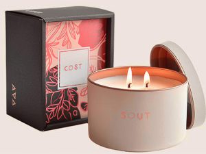 White and gold two-wick candle inside a premium box with floral pattern and branding.